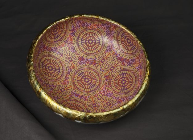 Buntes rotgoldfarbenes Muster in Decoupagetechnik auf einer flachen Holz-Schale mit goldener Umrandung.