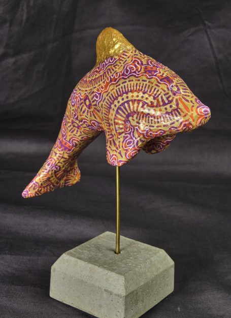Bunt verzierter Fisch mit goldenen Akzenten auf einem stabilen Beton-Sockel.