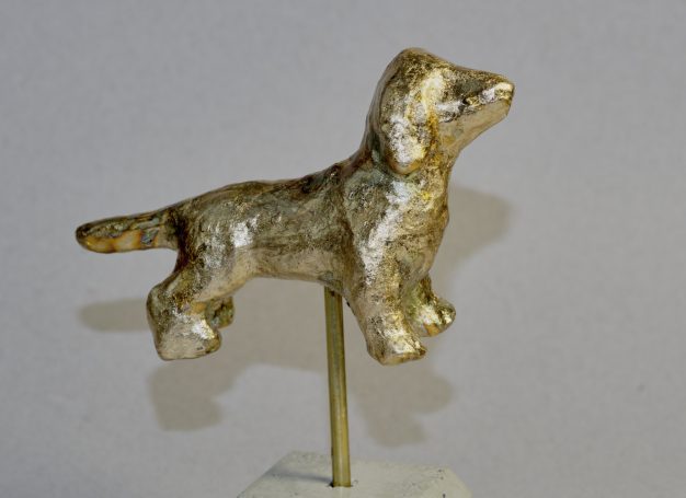 Eine kleine Statue eines stehenden Dackels in Goldbraun